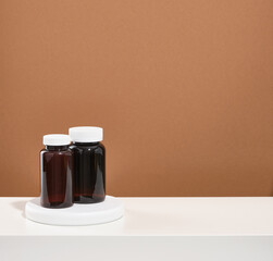 Two medical jars of brown with white lids with pills stand on a white table. Copy space for text. Treatment and prevention.