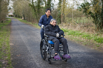 Elderly Indian woman in a wheelchair with daughter carer, UK