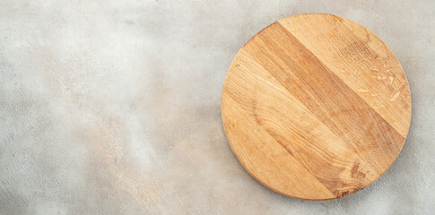 Empty wooden round board on light kitchen table. Wooden pizza platter, Long banner format. top view