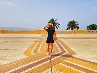 woman from behind with hat standing on the colored mosaic of the square of Ajaccio in Corsica
