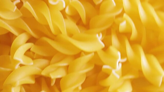 Uncooked Fusilli Pasta - Top View. Fat And Unhealthy Food. Dry Spiral Macaroni, Moving Background. Italian Culture And Cuisine. Raw Golden Pasta Pattern. Upward Movement