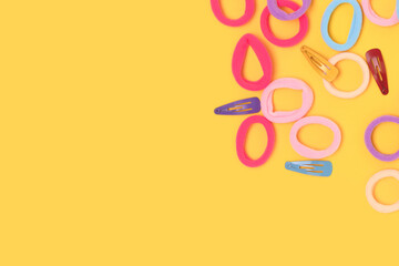 Naklejka premium Small multicolored hair scrunchies and clips on a yellow background. Place for text.