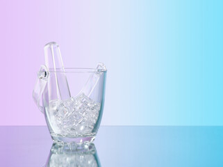 Composition of glass ice bucket and ice tongs for making alcoholic drinks at a party. Copy space for text.