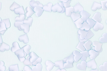 Round frame made of textile confetti in a heart shape on a blue background. Place for your design.