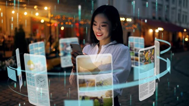 An incredibly beautiful Asian woman is using an augmented reality phone to browse web pages, apps, and social networks. Woman uses the gadget while standing in the middle of a city street at night