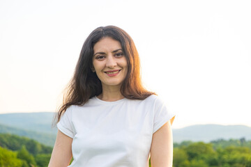 Portrait of a 35-year-old European woman smiling while looking at the camera while walking in nature in a field.