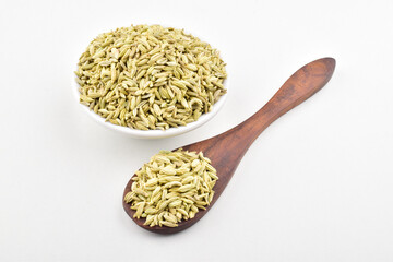 Aromatic fennel seeds in wooden spoon on white background