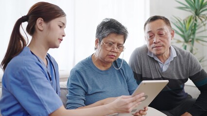 Asian female nurse caregiver is describing condition health of the elderly old couple on tablet. Homecare nursing service and elderly people health care. Elderly care concept