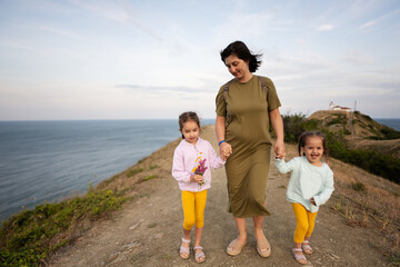 Mother and two daughters walking on a path by the sea in the evening. Cape Emine, Black sea coast, Bulgaria.