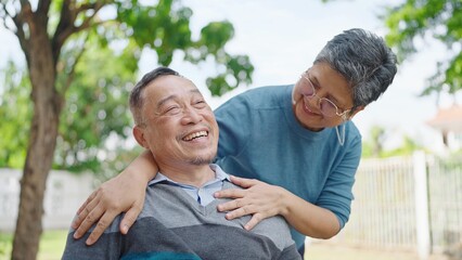 Happy asian elderly married couple relaxing in park together. Cheerful asian adult male patient...