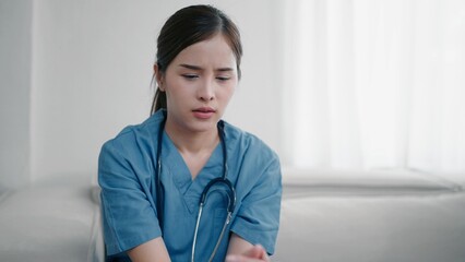 Tired depressed young asian woman nurse suffer after hard working. Exhausted sad woman doctor feels...