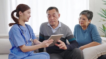 Asian female nurse caregiver is describing condition health of the elderly old couple on tablet....
