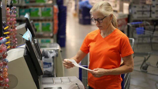 Mature woman at the self checkout cash register getting receipt in a big box hardware store.