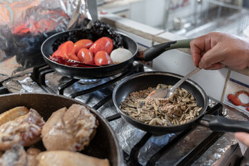 An adult Hispanic woman is heating sesame and seeds to prepare mole