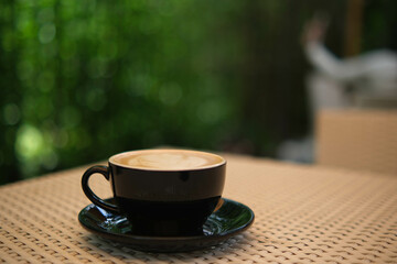 cup of coffee in a black mug in the garden