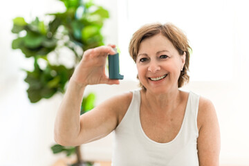 Elderly woman using asthma inhaler in clinic
