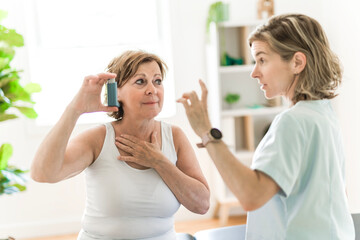 Elderly woman using asthma inhaler in clinic