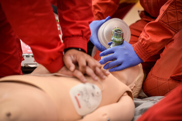 Paramedics simulate emergency intervention on medical training manikin - 625200733