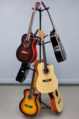 Acoustic guitars of different sizes and colors on a stand in a musical instrument store