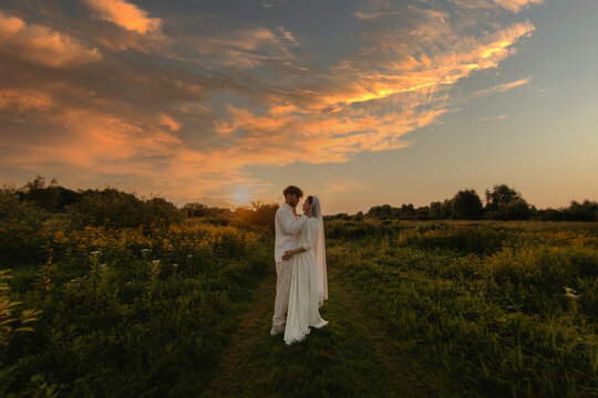 loving couple of newlyweds at sunset in the field, the bride and groom in white wedding.