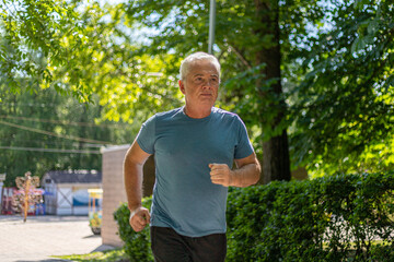 gray-haired man 50 years old jogging in the park in summer