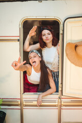 Happy hippie friends are having a good time together in a camper trailer. Holiday, vacation, trip concept.