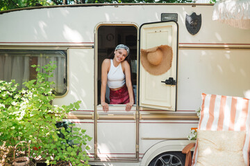Happy hippie girl is having a good time in a camper trailer. Holiday, vacation, trip concept.