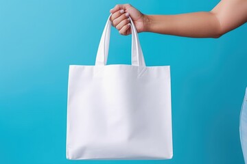 The hand is holding a canvas tote bag for a mockup. shopping bag canvas. blue background.