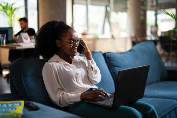 Black businesswoman working on laptop. Portrait of beautiful businesswoman talking to the phone in the office.