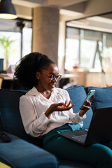 Black businesswoman working on laptop. Portrait of beautiful businesswoman using the phone in the office.