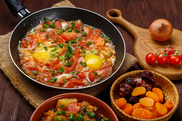 Jewish food hot cholent and shakshuka in a frying pan on a set Shabbat table.