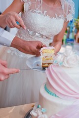 The hands of a wedding couple cutting a wedding cake. Vertical photo