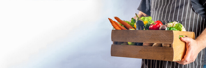 Farm organic market shopping concept, Wooden box with summer, autumn raw vegetables and fruits, in farmer mans hands on white background