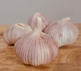 3 heads of garlic are placed on a cutting board.