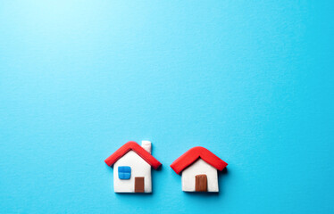 Fototapeta na wymiar Two houses on a blue background. Place for text. Find most suitable housing options. Mortgage. Valuation of residential buildings. Realtor services. Buying and selling. Offers on real estate market.