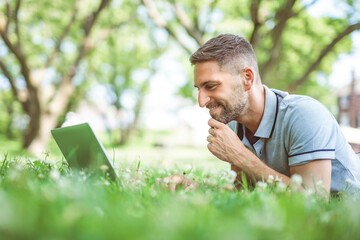 Happy cheerful man with a laptop outdoors in nature, freedom and happiness concept