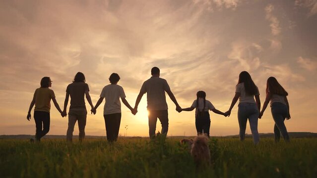 community big family in the park. large group of lifestyle people sunset holding hands walking silhouette nature in the park. big family childhood dream concept. people in the park. big family
