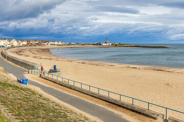 Newbiggin Bay and it's lovely sandy beach at Newbiggin-by-the-Sea, Northumberland. Taken on a bright but chilly spring day.  - obrazy, fototapety, plakaty