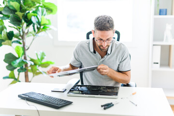 Handsome engineer repairing laptop computer.