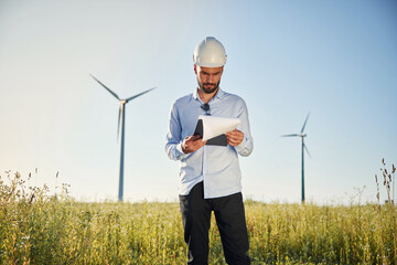 On the field with windmills. Service engineer with notepad in hands