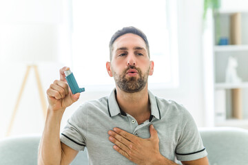 man using asthma inhaler at home - obrazy, fototapety, plakaty