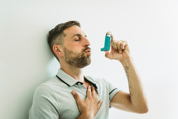 man using asthma inhaler at home