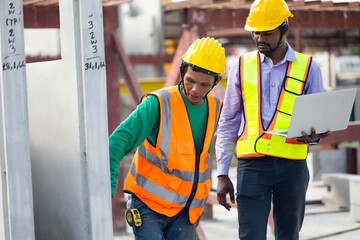Asian indian construction architect Engineering man and senior worker in safety hardhat working on laptop computer at Prefabricated concrete factory Heavy industrial
