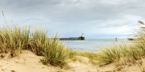 Fototapeta na wymiar Blyth piers and lighthouse, seen from the dunes and marram grass beach.