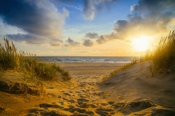 Weg zwischen den Dünen führt zum Strand bei Sonnenuntergang 