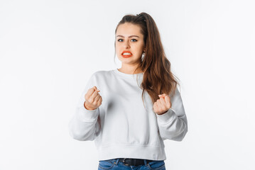 Pissed-off girl gesticulating with her hands, stands over white background. Distressed and irritated female in white sweatshirt squeeze hands in fists losing patience, boiling from annoyance - obrazy, fototapety, plakaty