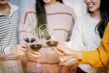 Cheerful friends enjoying home Birthday holiday party. Asian Friends cheering drinking red wine celebrating Christmas or New Year party