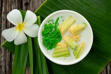 Lod Chong of Thai dessert with pandan leaf followed by green banana leaves on the wood background.