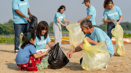 group of diverse volunteers charitable working together to clean up river beach, senior adult and girls picking trash into garbage bags separating reused plastic for recycling waste management