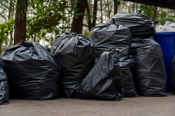 pile of disposable black garbage bags placed on ground around camping area full of trash separated...